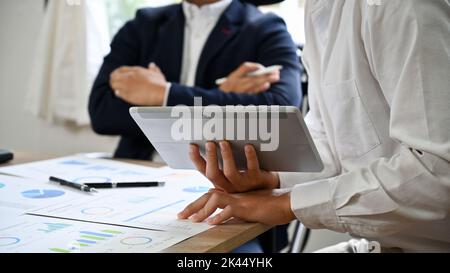 Ein junger asiatischer Geschäftsmann oder Marketingmitarbeiter präsentiert und teilt seine Ideen mit den Vorstandsmitgliedern in der Sitzung. Zugeschnittenes Bild Stockfoto
