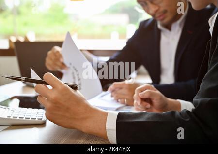 Professionelle und intelligente asiatische männliche Finanzberater analysieren Finanzdaten zum Bericht, treffen sich und arbeiten zusammen. Nahaufnahme und zugeschnittenes Bild Stockfoto