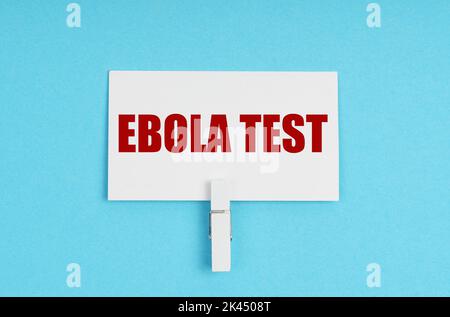 Medizinkonzept. Auf blauem Hintergrund befinden sich Pillen und eine Visitenkarte mit der Aufschrift - ebola-Test Stockfoto