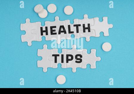 Medizinkonzept. Auf blauem Hintergrund Pillen und Puzzles mit der Aufschrift - GESUNDHEITSTIPPS Stockfoto