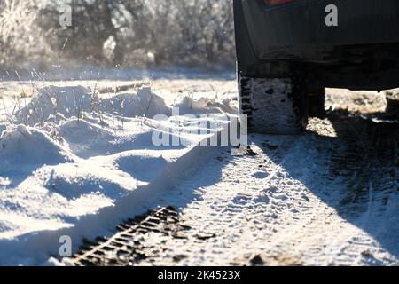 Autoräder Schnee Nahaufnahme. Fahren auf einer Winterstraße. Winterreifen schießen aus einem niedrigeren Winkel. Das Konzept des Reisens, der Verkehrssicherheit, des Reisens mit dem Auto. Stockfoto