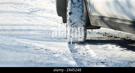 Autoräder Schnee Nahaufnahme. Fahren auf einer Winterstraße. Winterreifen schießen aus einem niedrigeren Winkel. Das Konzept des Reisens, der Verkehrssicherheit, des Reisens mit dem Auto. Stockfoto