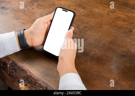 Modernes Smartphone-Modell, Nahaufnahme Foto von Frau mit vertikalem modernen Smartphone-Modell. Holztisch sitzend, weißer leerer Bildschirm. Stockfoto