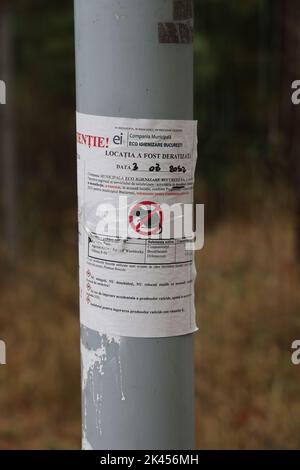 Ein offizielles Plakat (Papiermitteilung) von Stadtbehörden, das vor Rattengift warnt, das verwendet wurde; an einem Pol in einem Park in Bukarest, Rumänien Stockfoto