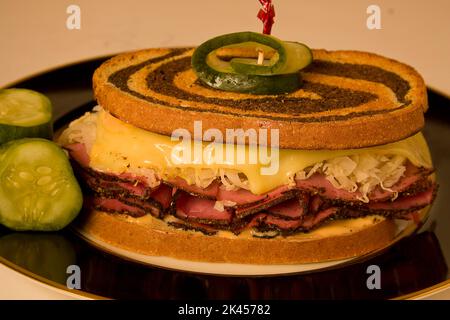 Großes reuben-Sandwich auf einem schwarzen Teller mit geschmolzenem schweizer Käse auf Roggen. Stockfoto