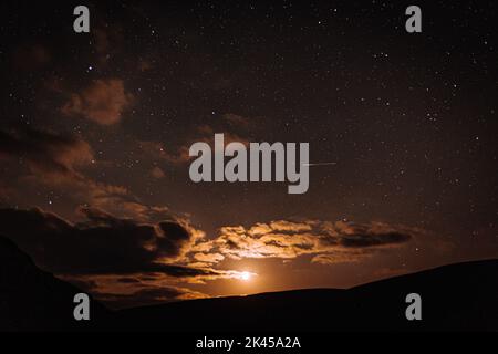 Der dunkle Himmel mit der untergehenden Sonne hinter den Wolken Stockfoto