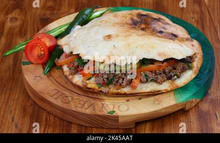 Rolle gefüllt mit Shish Kebab mit Tomaten, Kräutern, Ketchup und Amyonnaise auf einem Holztisch Stockfoto