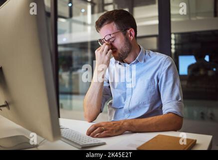 Nachtarbeit, Stress und müde Mann, der an seinem Computertisch sitzt, mit Kopfschmerzen, Depressionen und Burnout vom Arbeitsdruck. Gestresst, psychische Gesundheit Stockfoto