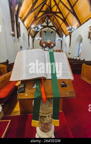 Eine bibel sitzt auf einer Kanzel, die bei Römer 13, 14 und 15 geöffnet ist. Stockfoto