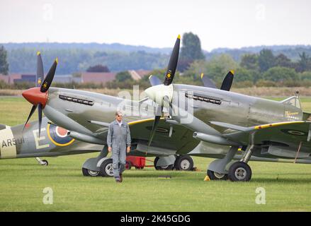 WW2 Flugzeuge; - Spitfires UK; Ein Mann, der am Boden an zwei Spitfires vorbeiläuft, Szene auf einer Flugshow, Imperial war Museum, Duxford UK Stockfoto