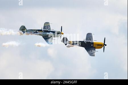 Zwei Hispano HA-1112 Buchon-Flugzeuge - ein Militärflugzeug in deutscher Farbe aus dem Jahr 1950s, das auf der Duxford Airshow, Imperial war Museum, Duxford Cambridgeshire UK, fliegt Stockfoto