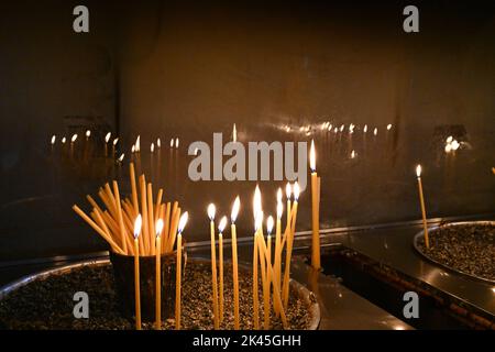 Dünne lange Kerzen brennen in einer Kirche. Nahaufnahme. Stockfoto