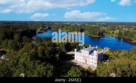 Luftaufnahme des Birinu-Palastes. Lettische Burg am See mit hübscher Gartenanlage, Drohnenaufnahme. Birini Manor, Region Vidzeme, Lettland. Sonniger Herbsttag Stockfoto