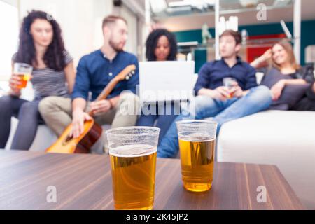 Gruppe von Freunden mit Spaß trinken Bier und Gitarre spielen auf der Couch. Verschwommenes Bild Stockfoto