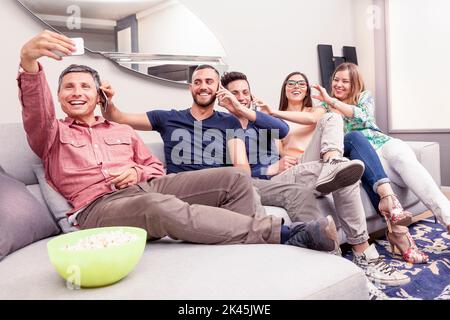 Eine Gruppe von Freunden auf der Couch macht ein Selfie auf lustige Weise Stockfoto