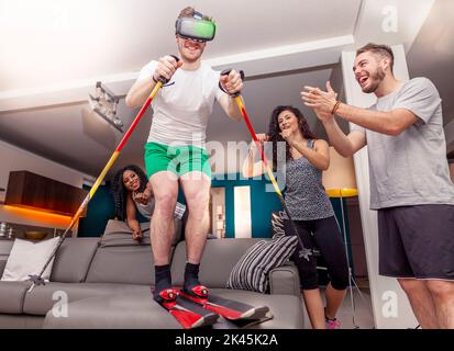 Gruppe von Freunden, die Spaß zu Hause Skifahren mit Viewer für virtuelle Realität Stockfoto