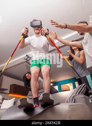 Gruppe von Freunden, die Spaß zu Hause Skifahren mit Viewer für virtuelle Realität Stockfoto