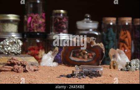 Flasche Chakra-Steine auf rotem Sand mit agatisierter Koralle im Hintergrund mit flachem Innengewinde Stockfoto