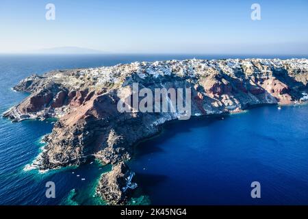Luftaufnahme einer Insel im tiefblauen Meer der Ägäis, Felsformationen, weiß getünchte Häuser auf den Klippen. Stockfoto