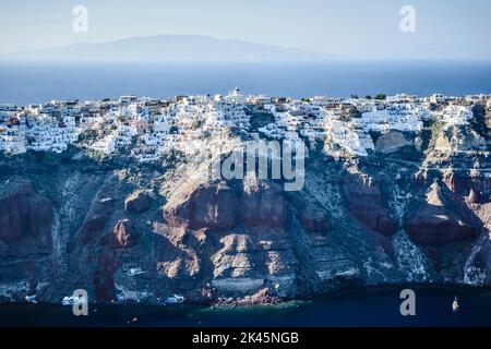 Luftaufnahme einer Insel im tiefblauen Meer der Ägäis, Felsformationen, weiß getünchte Häuser auf den Klippen. Stockfoto