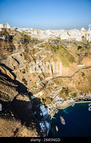 Luftaufnahme einer Stadt auf einer steilen Klippe auf der Insel Egeo und der gewundene Weg zu den Häusern vom Landepunkt an der Küste. Stockfoto