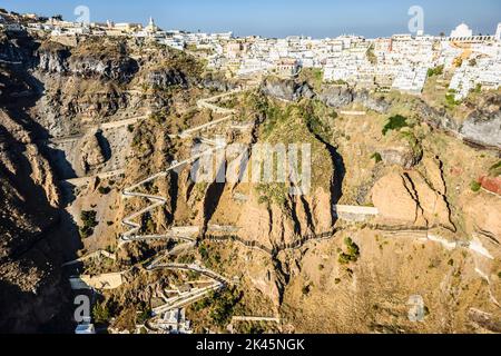 Luftaufnahme einer Stadt auf einer steilen Klippe auf der Insel Egeo und der gewundene Weg zu den Häusern vom Landepunkt an der Küste. Stockfoto