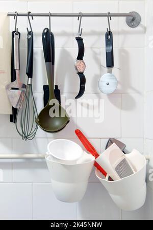 Armbanduhr, die auf einem Gestell zwischen verschiedenen Küchengeräten hängt Stockfoto