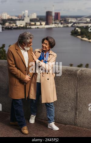 In voller Länge eine glückliche ältere Frau, die einen bärtigen Ehemann in der Nähe des Flusses ansieht, Stockbild Stockfoto