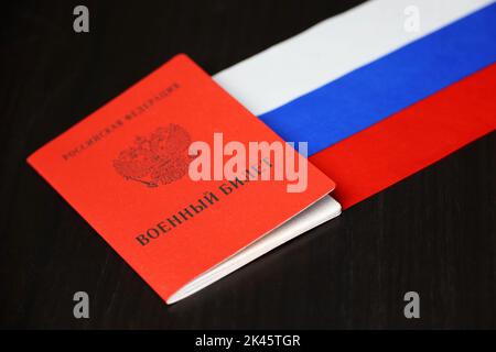 Russischer Militärausweis und Nationalflagge auf Holztisch. Konzept der Mobilisierung in Russland Stockfoto