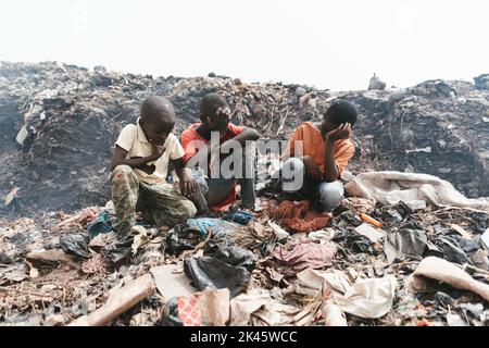 Drei afrikanische Jungen, die mit einem traurigen Gesicht auf einer Müllhalde außerhalb von Bamako, Mali, sitzen Stockfoto