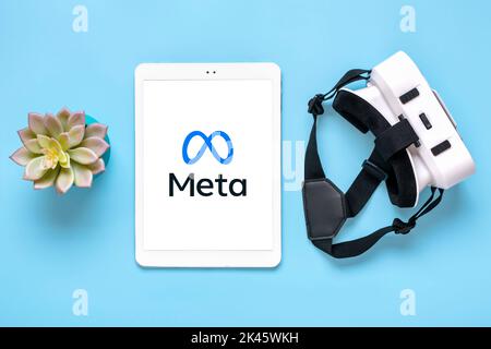 April 2022, Kanada. Weißes Tablet mit Meta-Logo-Bildschirm auf digitalem Display, VR-Brille für Virtual-Reality-Spiele auf blauem Hintergrund Rebranding von Social Media Facebook. Stockfoto