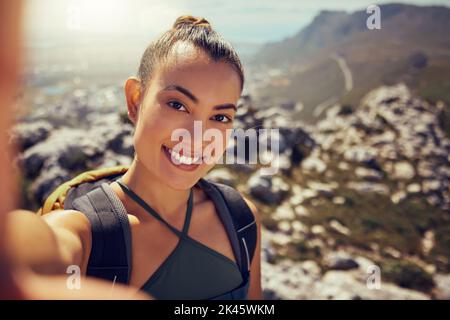 Porträt, glücklich und Frau wandern mit einem Selfie in der Natur auf einem Berg im Sommer. Gesicht, Fitness und Bewegung Latino Frau oder Tourist lächeln, während Stockfoto