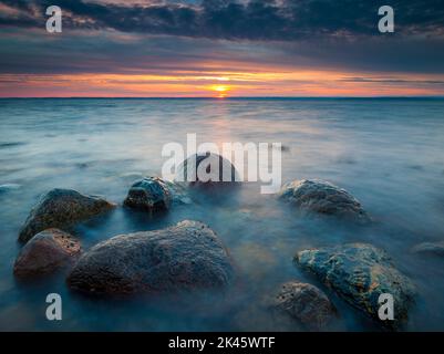 Farbenfroher Herbstuntergang an der Küste mit nassen Felsen und Meeresbrandung am Botnerbaugen in Larkollen, auf der Ostseite des Oslofjord, Østfold fylke, Norwegen. Stockfoto