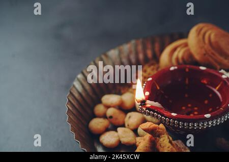 Diwali Snacks mit Diya Lampe beleuchtet - Deepavali Hintergrund, selektive Focu Stockfoto