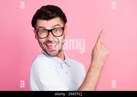 Nahaufnahme Foto von jungen attraktiven schönen Kerl tragen weißen Polo-T-Shirt aufgeregt Finger zeigt leeren Raum neuen Vorschlag auf rosa Farbe isoliert Stockfoto