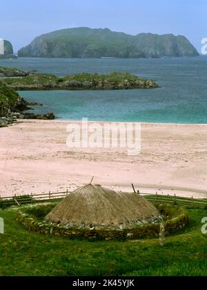 Replik Iron Age (Pictish) Acht-Haus am Kopf von Bosta (Bostadh Beach, Bernera, Isle of Lewis, Schottland, Großbritannien, Blick nordwestlich auf Old Hill Island. Stockfoto