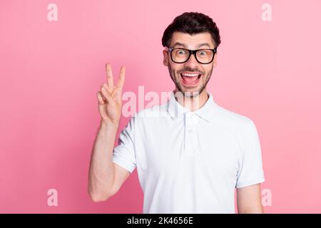 Portrait Foto von jungen attraktiven schönen Mann tragen Brillen offenen Mund aufgeregt nett V-Zeichen Symbol positive Hallo isoliert auf hellen rosa Farbe Stockfoto