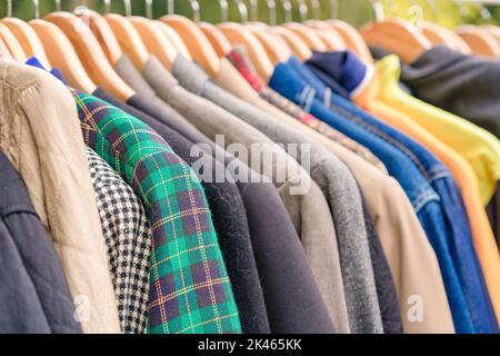 Kleidung an Kleiderbügeln – Second Hand-Bekleidungsgeschäft oder Sparsamkeit-Shopping-Konzept. Kleiderverleih. Vintage Jacken zum Verkauf auf dem Flohmarkt. Selektiv Stockfoto