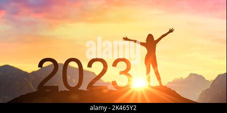 Neujahr 2023, New Start Motivation inspirierende Zitat-Nachricht über die Silhouette der Gewinnerin Frau im Sonnenuntergang mit den Armen im Glück. Willkommen Happy New y Stockfoto