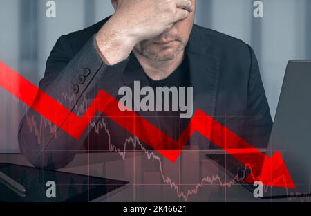 Ein niedergedrückter Geschäftsmann, der die Hände auf dem Kopf hielt und sich die abfallende Grafik ansah. Börsenwertverlust Trading Graph Analyse Investmentindikator Stockfoto