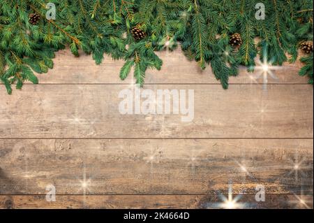 Vorlage für Weihnachtshintergrund. Rahmen aus Tannenzweigen mit Sternen auf braunem Holztisch. Tannenzweig mit Weihnachtsschmuck. Festliche Weihnachten Stockfoto