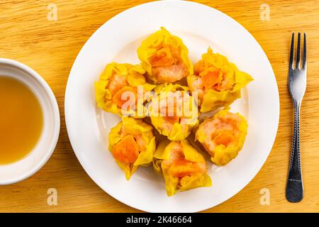 Draufsicht, flaches Lay frisch leckere hausgemachte Garnelen, gehacktes Schweinefleisch und gesalzenes Eigelb gedämpfte Knödel in weißer Keramikschale mit Sauce in weißer Cerami Stockfoto