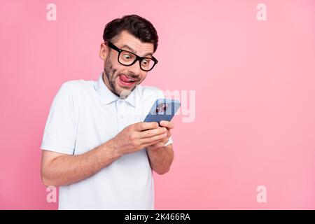 Foto von cool nett aufgeregt Mann Hand halten Telefon verwenden Gerät Gadget schreiben SMS Freundin leeren Raum auf rosa Hintergrund isoliert Stockfoto