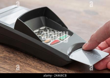 Nahaufnahme der Person Einlegen der Kredit- oder Debitkarte in den Kartenleser, bargeldloses Zahlungskonzept Stockfoto