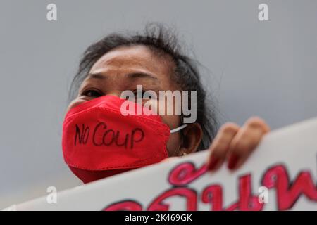 Bangkok, Thailand. 30. September 2022. Eine Protesterin sah, wie sie während der Demonstration eine Maske trug, auf der „kein Coup“ steht, als sie ein Plakat hielt. Aufgrund der Tatsache, dass das thailändische Verfassungsgericht mit Mehrheit das Urteil verkündete, dass die 8-jährige Amtszeit von Premierminister Prayut Chan-o-cha gemäß der Verfassung von 2017 nicht am 24.. August auslief. Das macht Prayut Chan-O-cha immer noch in der Position des Premierministers. Danach versammelten sich prodemokratische Demonstranten an der Kreuzung Pathumwan und forderten den Rücktritt von Premierminister Prayut Chan-O-cha. Kredit: SOPA Images Limited/Alamy Live Nachrichten Stockfoto