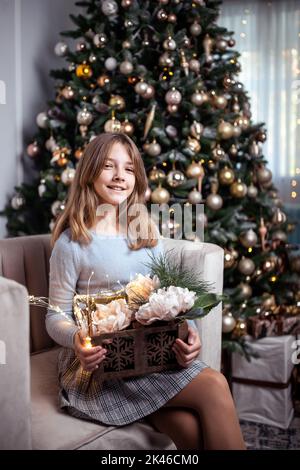 Nettes Teenager-Mädchen in einem Zimmer mit einem geschmückten Weihnachtsbaum. Die Winterferien. Stockfoto