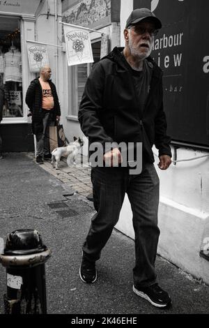 Alter Mann, der mit dem Mann hinter dem Hund läuft Stockfoto