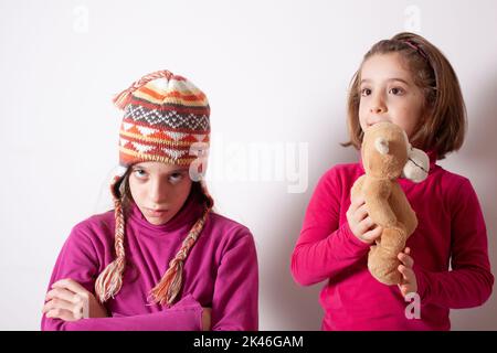 Gieriges Kinderkonzept. Beziehungen der Schwestern. Teile Spielzeuge mit Freunden. Kinder auf weißem Hintergrund spielen mit Spielzeug Stockfoto