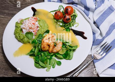 Salat mit Krabben, Gurken, Cocktailgarnelen, Avocado-Tatar und Mangosauce. Blick von etwas oben. Frische und saftige Lebensmittel. Hausgemachte leckere fo Stockfoto