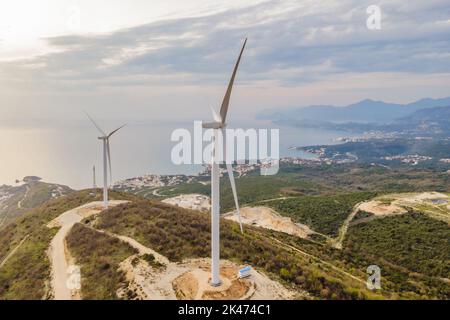 Windturbinen auf schönen sonnigen Sommer Herbst Berglandsland. Kurvige Straße durch den Berg Eolic Park. Grüne ökologische Energieerzeugung Stockfoto